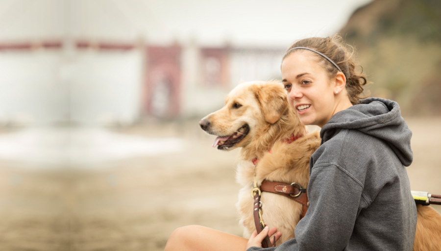 Kvinne sitter ute med hunden i bånd ved siden av seg