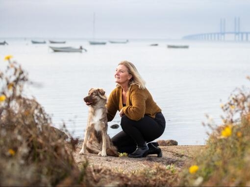 Kvinne sitter med hund ved Øresundsbroen