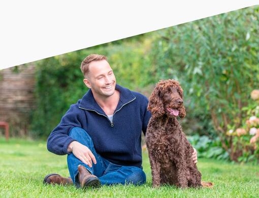 Mannen og hunden hans sitter på gresset